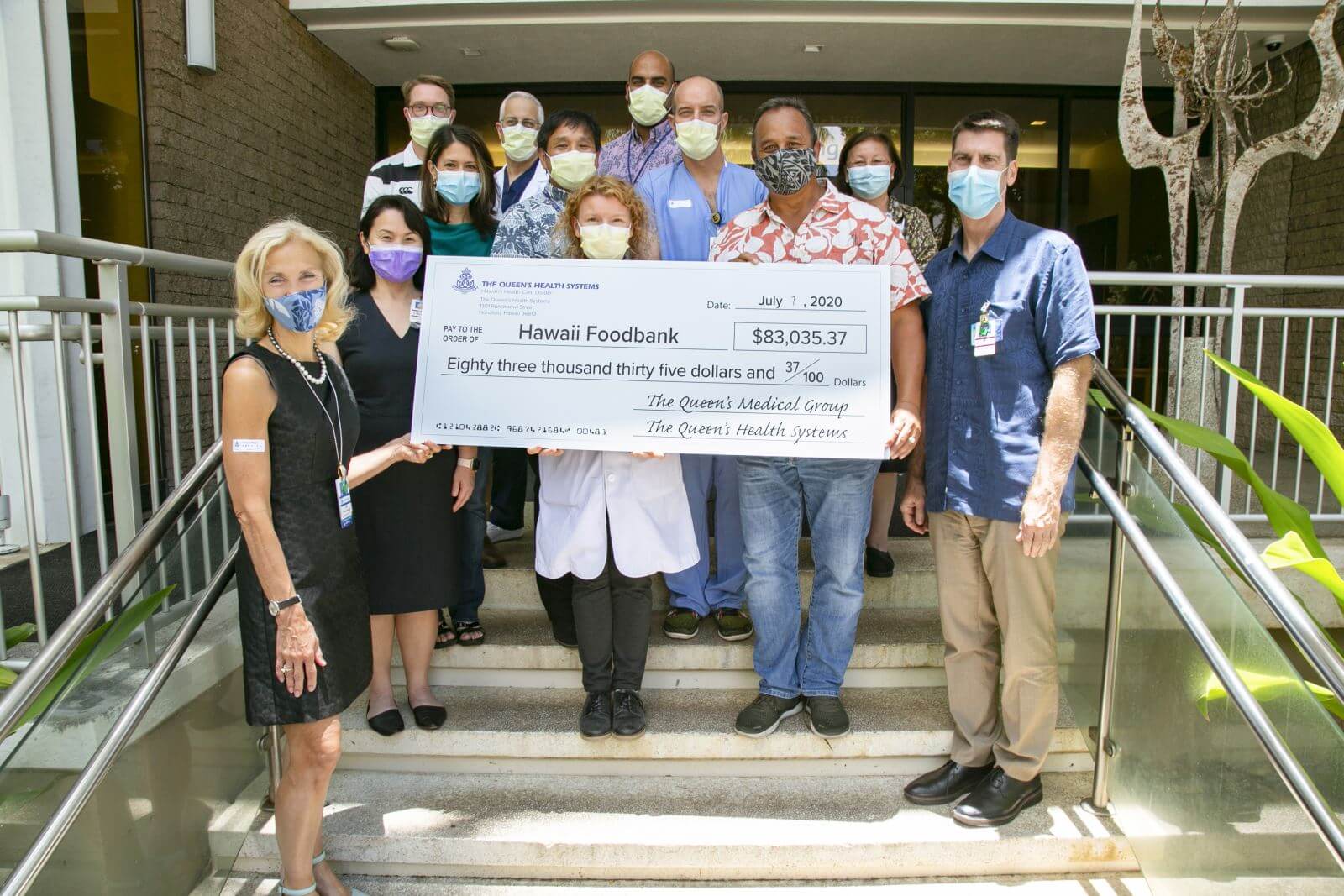 Employees and CEO Dr. Jill Hoggard Green standing with a large check for the Hawaii Foodbank to the amount $83,035.37