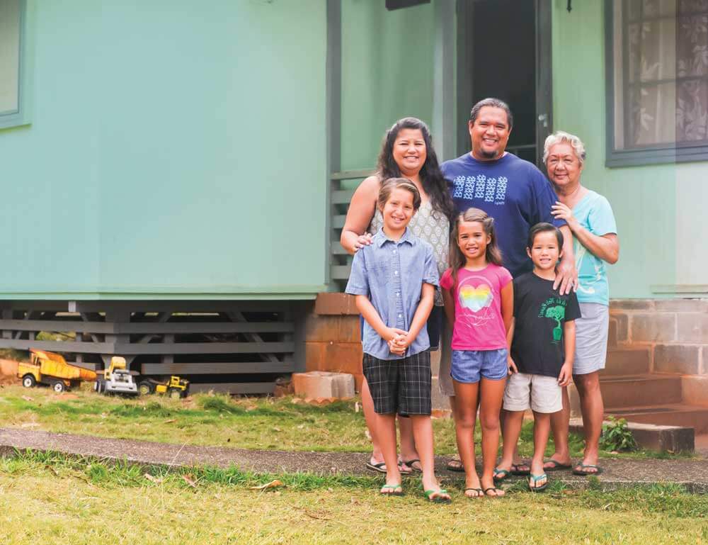 Family of 5 and grandmother standing in front of their home.