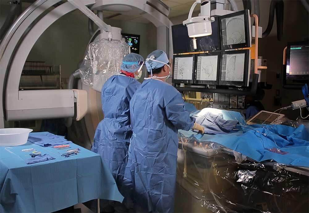 Neurologist looking at monitors while conducting a procedure in operating room.