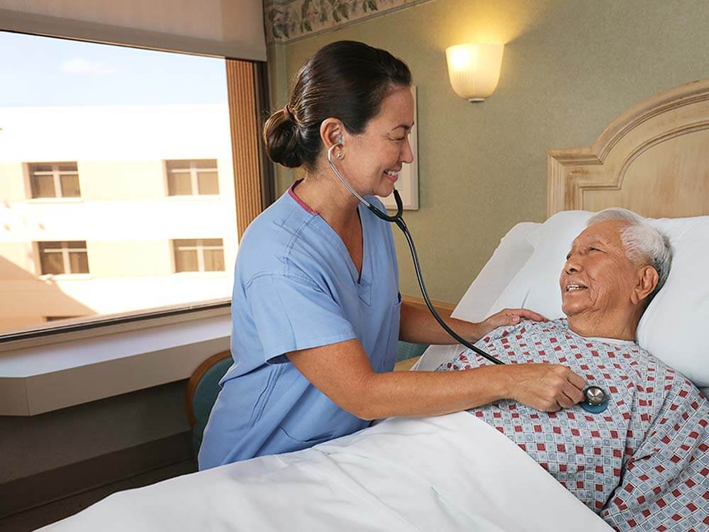 Nurse uses stethoscope on hospital patient