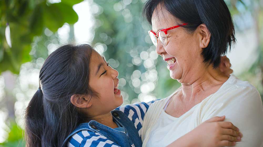 Girl and grandmother laughing while they hug