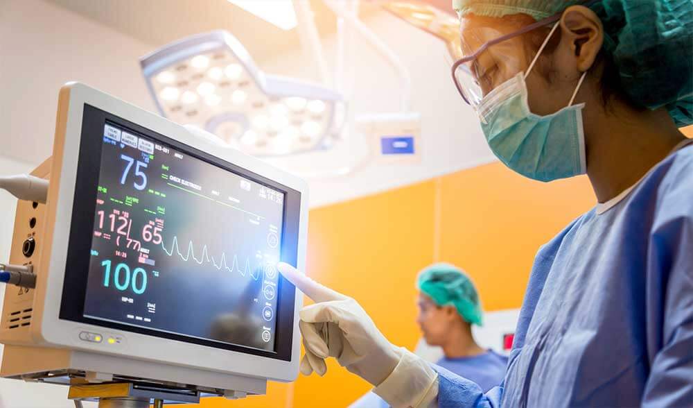 Female medical staff looking at heart monitor in OR.