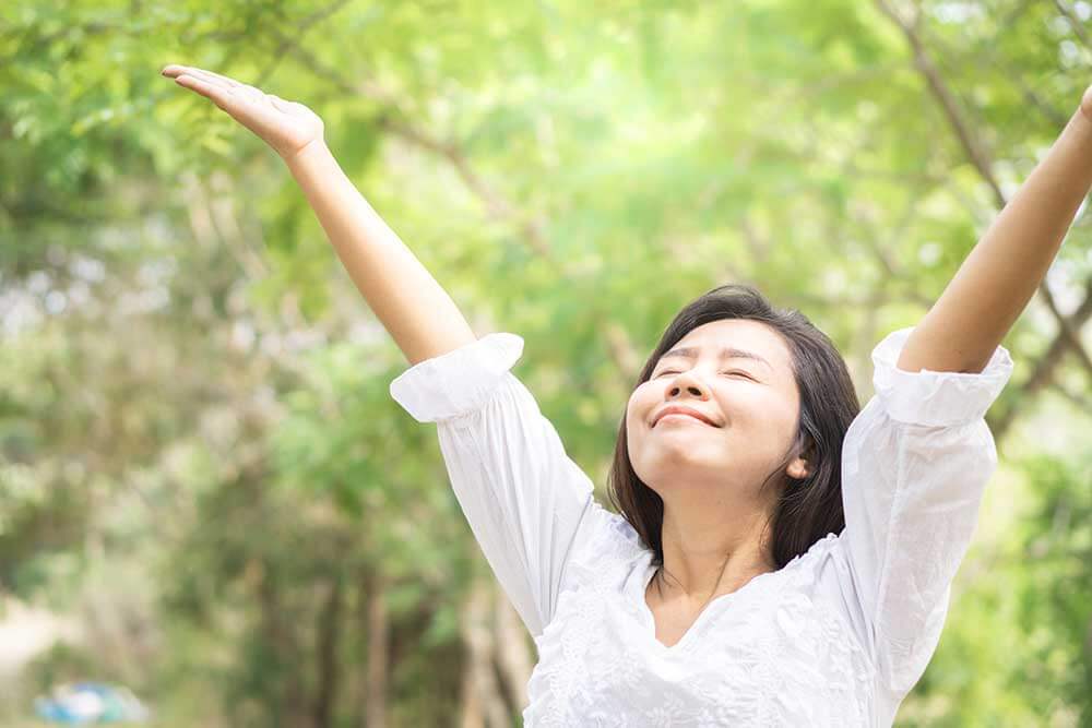 Woman breathing in air with arms open