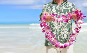 Man holding out a lei on the beach