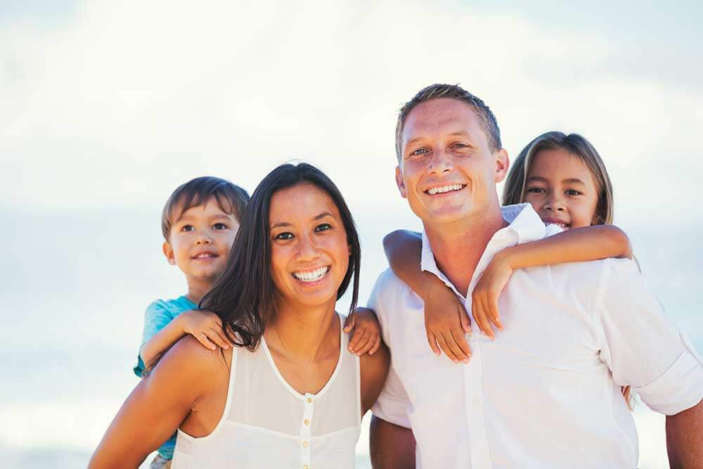 Family of four smiling at the beach