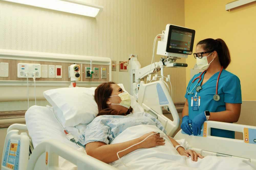 Female patient in a hospital bed talking with her Physician