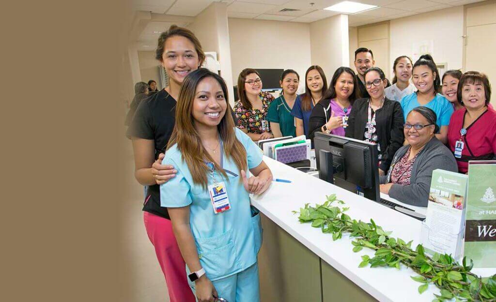 Group photo of nursing staff standing at reception desk .