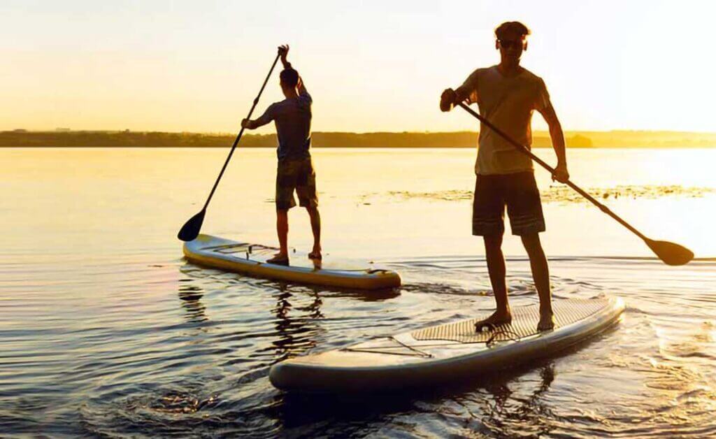 Two stand up paddle boarders at sunset.