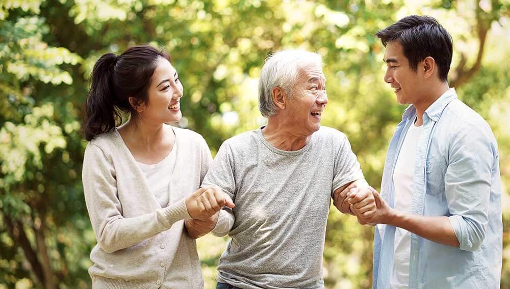 Sister and brother help guide their senior father on a walk