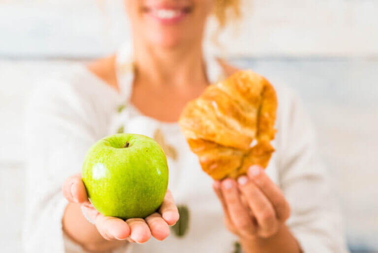 Woman choosing an apple over croissant