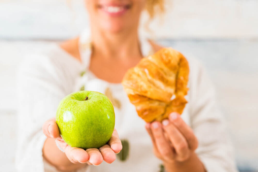 Woman choosing an apple over croissant